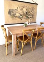 A provincial farmhouse style wooden table with tapered legs, accompanied by matching chairs. Solid wood