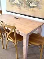 A provincial farmhouse style wooden table with tapered legs, accompanied by matching chairs. Solid wood