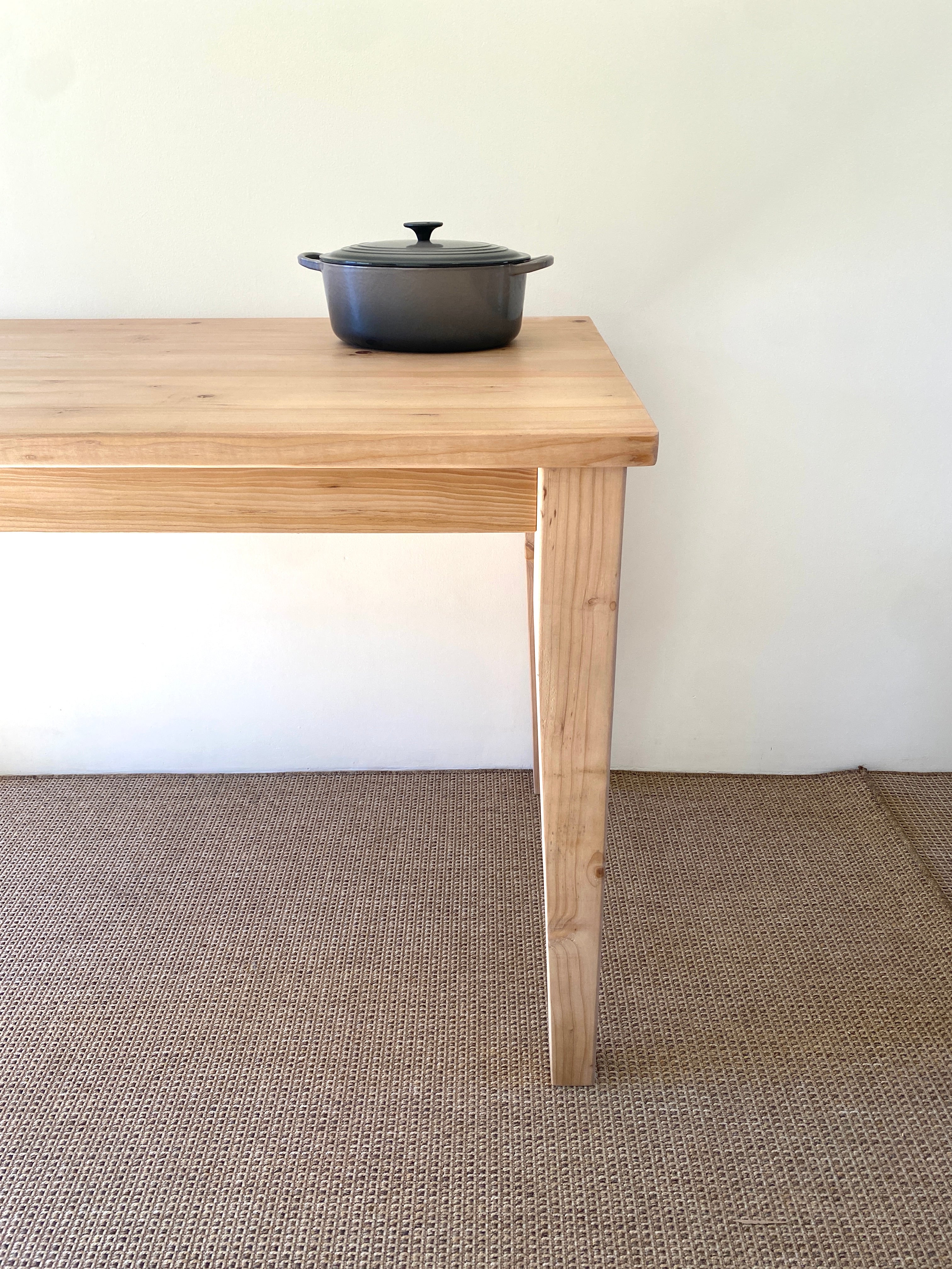 A Provincial farmhouse style kitchen island made of solid wood with a cast iron Le Creuset pot on top, placed on the table top.